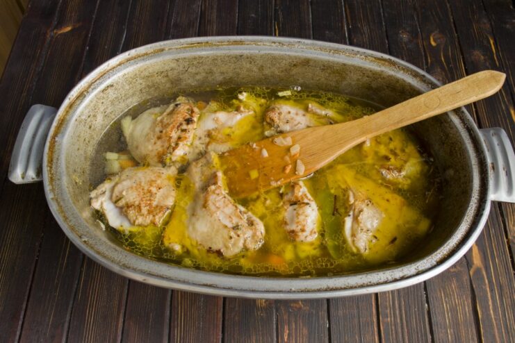 Adding hot water to cover the chicken and vegetables for the plov broth Hot water being poured over chicken and vegetables in a Dutch oven.