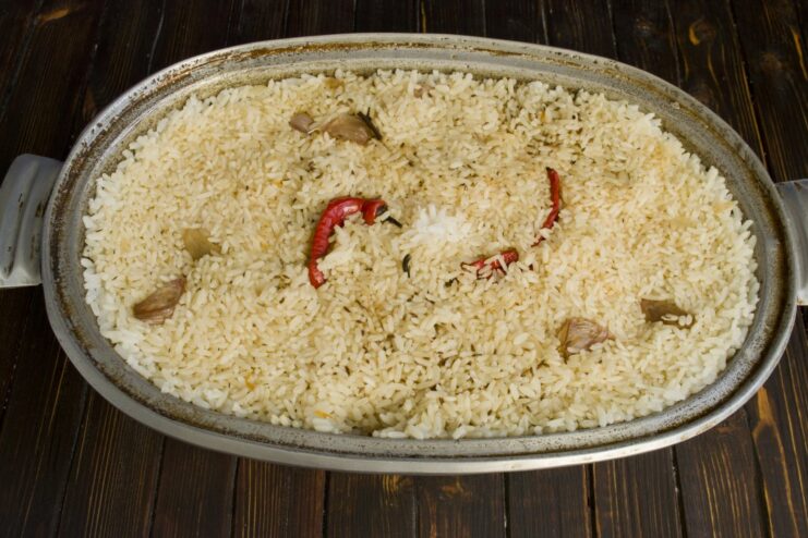 Simmering the plov under a closed lid until the rice is perfectly cooked The plov simmering gently in the Dutch oven, with steam rising from the rice.