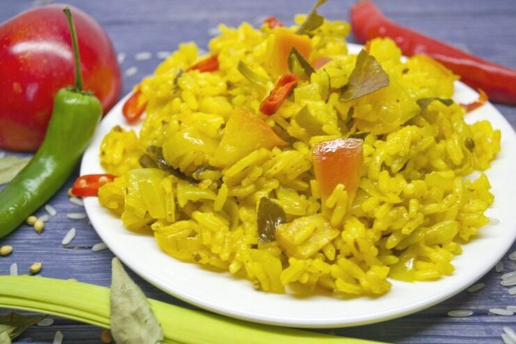 A bowl of vibrant yellow vegetarian curry rice with apples, ready to be served.