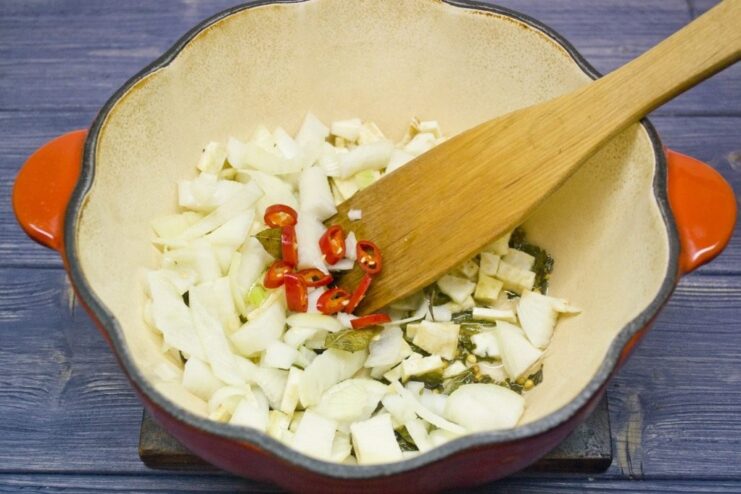 Building the flavor base for the curry rice Chopped celeriac, onion, and chili peppers being sautéed in a pot.