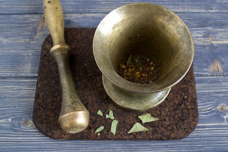 Using a mortar and pestle to create a fresh spice blend. Toasted spices being ground into a fine powder using a mortar and pestle.
