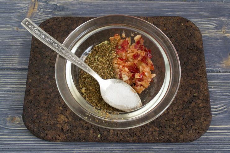Combining the spice paste with sugar and butter for the marinade. A bowl with a spice paste, with sugar and butter being added to it.