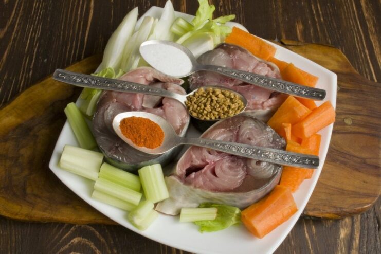 Seasoning Tuna and Veggies Before Baking Tuna steaks and vegetables seasoned with paprika and fenugreek.