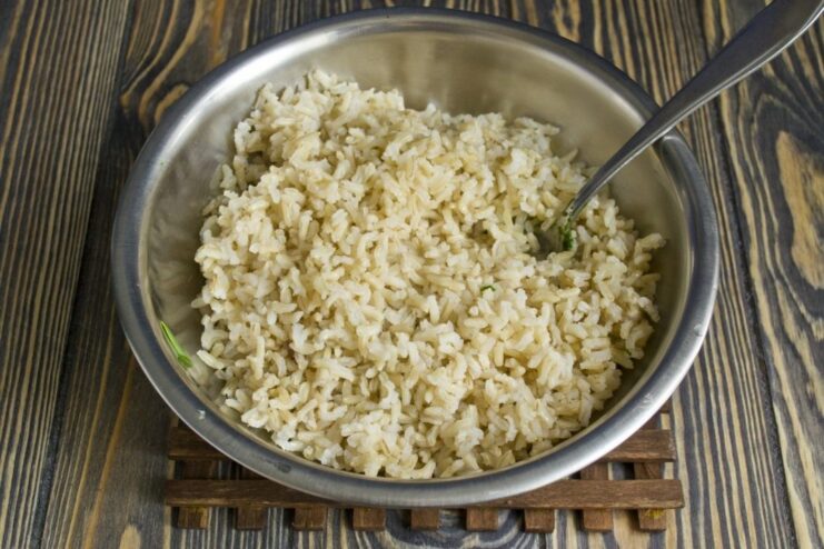 Brown rice cooking in a saucepan with butter and water.