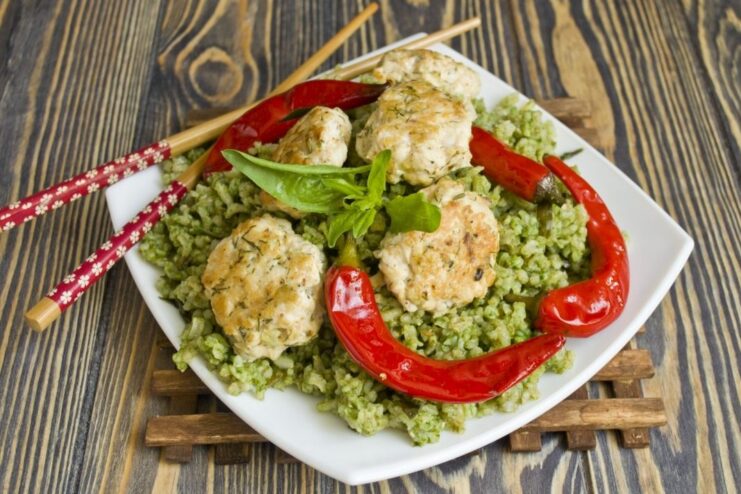 A close-up of the finished Green Rice with Meatballs, garnished and ready to eat.
