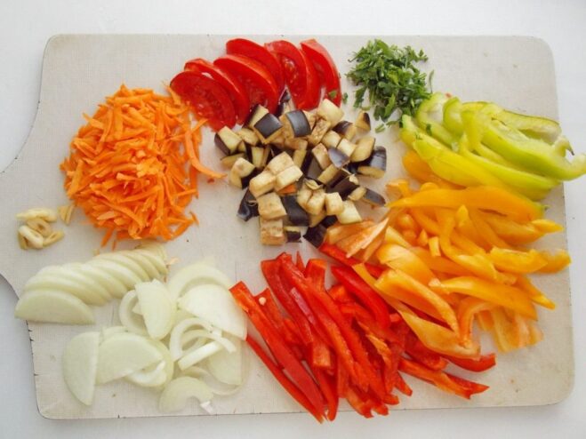 Chopping various vegetables to add to the potatoes A variety of chopped vegetables, including bell peppers and onions, ready to be cooked.