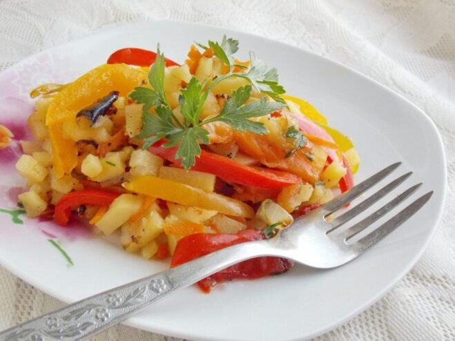 A close-up shot of a skillet filled with freshly cooked fried potatoes and assorted vegetables.