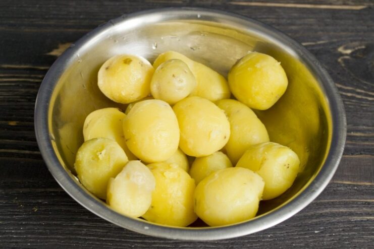 How to Easily Peel Boiled New Potatoes A hand easily peeling the skin off a small, boiled new potato.