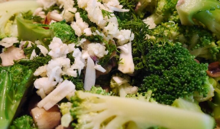 The final step: combining broccoli, mushrooms, and garlic in the pan for a quick sauté. Broccoli florets and mushrooms being sautéed together in a pan with garlic and herbs.
