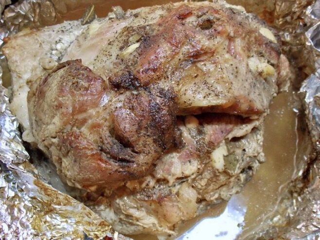 Let the Roasted Buzhenina Rest Before Slicing Freshly roasted buzhenina, unwrapped from foil, resting in a baking dish.