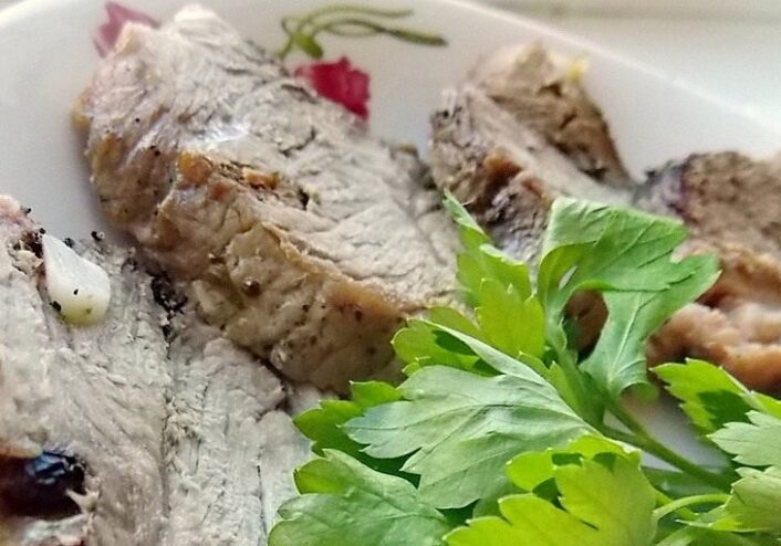 A plate of sliced homemade buzhenina, a traditional roasted pork dish, ready to be served.