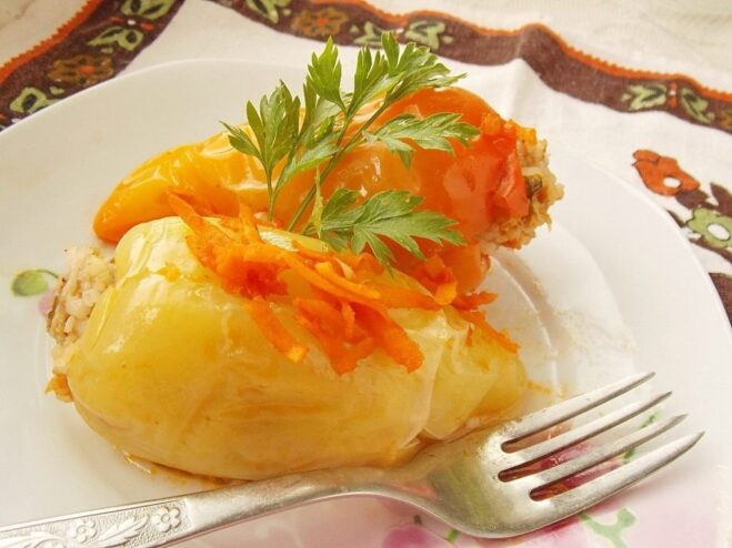 A plate of cooked stuffed peppers in a savory tomato sauce, garnished with fresh herbs.