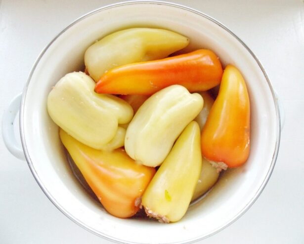 Arranging Stuffed Peppers in a Pot for Stewing Raw stuffed peppers arranged snugly in a large pot, ready for cooking.