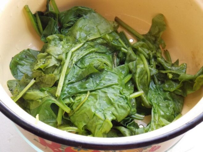 How to properly blanch fresh spinach leaves Fresh spinach leaves being blanched in a pot of boiling water.