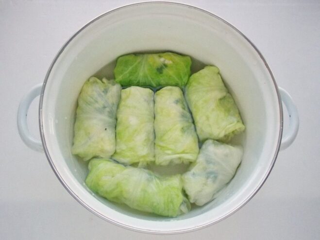 Arranging cabbage rolls in a pot for cooking Neatly rolled golubtsy arranged snugly in a single layer inside a large pot.