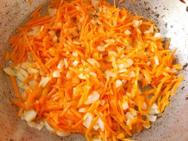 How to make a perfect zazharka (sautéed vegetable base) Sautéing onions and carrots in a frying pan to create a flavorful base.