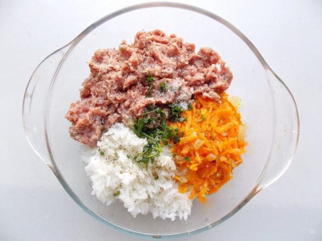 Combining ground meat, rice, and vegetables for the filling A bowl with ground meat, cooked rice, and sautéed vegetables being mixed together.