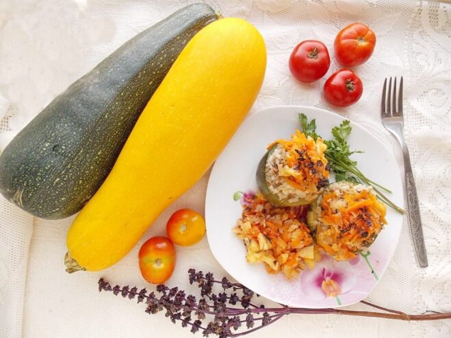 A plate of cooked stuffed zucchini in a tomato sauce, garnished with fresh herbs.