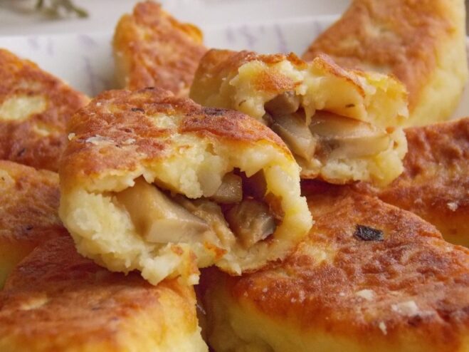 A plate of golden-brown potato zrazy with a mushroom filling, garnished with fresh herbs.
