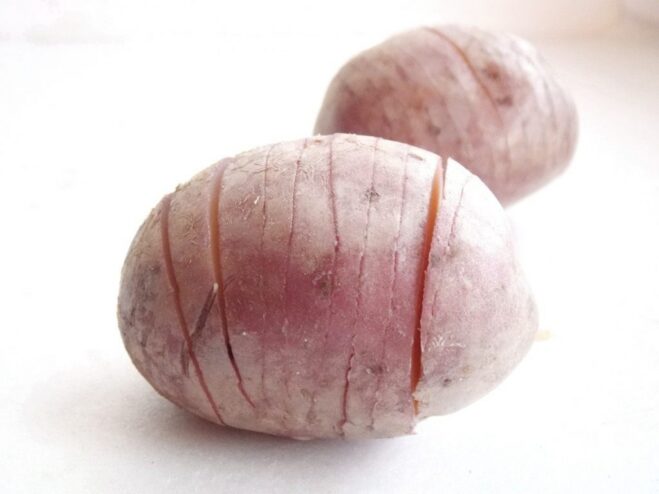 How to Slice Potatoes for the Accordion Effect A whole potato being sliced crosswise into thin sections, not cutting all the way through, to create an accordion shape.