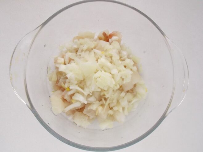 Adding Flavor: Mixing in Finely Chopped Onion Finely chopped onion being added to the bowl of diced fish.