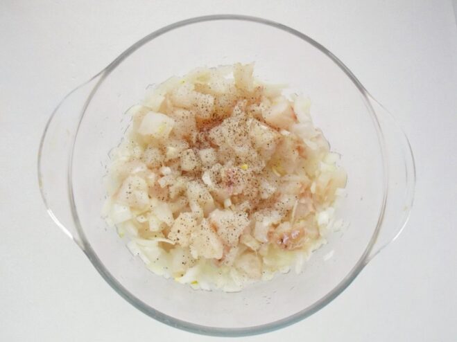 Seasoning the Fish Mixture for Perfect Flavor Salt and spices being sprinkled over the diced fish and onion mixture.