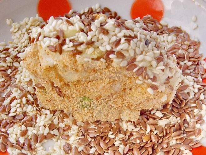 Adding a Nutty Crunch: Coating Cutlets in Seeds The sides of a fish cutlet being rolled in a mixture of sesame and flax seeds.