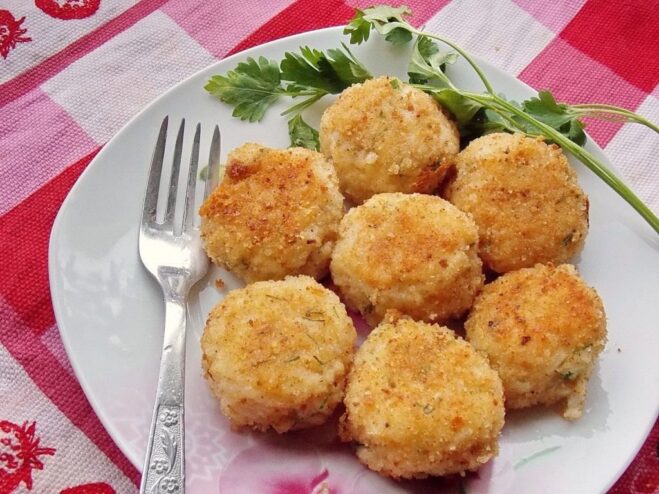 Serving suggestion for Celery and Rice Patties with sour cream A close-up of finished celery and rice patties on a white plate.
