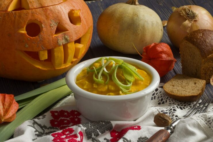 A white bowl filled with creamy chicken and pumpkin stew, garnished with fresh herbs.