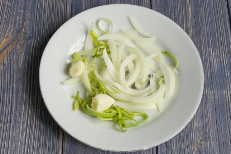 Preparing the Aromatic Base: Onion, Leek, and Garlic Chopped leek, sliced onion, and crushed garlic cloves ready for cooking.