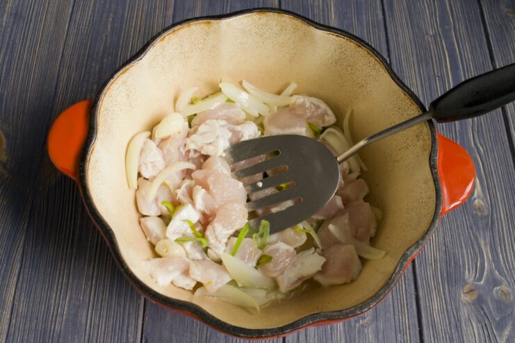 Sautéing Chicken and Aromatics in a Dutch Oven Sautéing chicken pieces with onion and garlic in a hot pot.