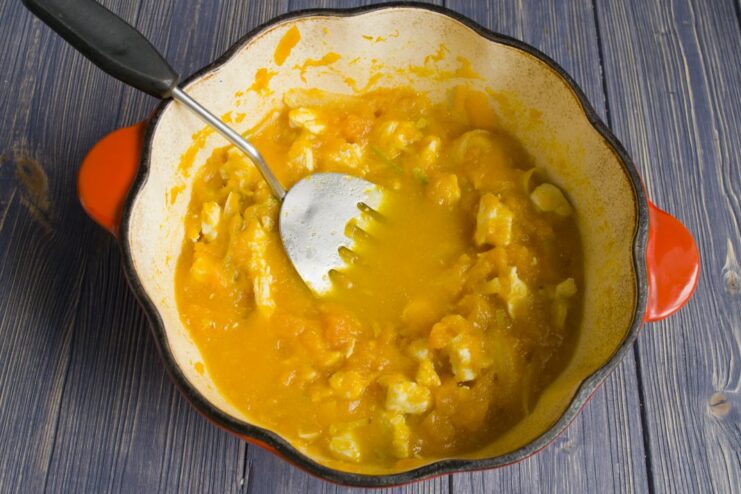 Stirring the Chicken and Pumpkin Stew as it Simmers A spoon stirring the chicken and pumpkin stew simmering in a pot.