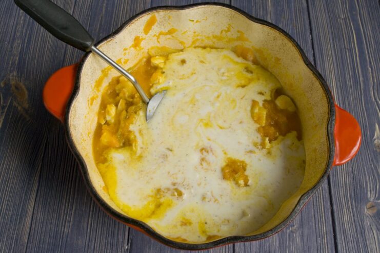 Adding the Creamy Smetana Sauce to the Stew Pouring a creamy smetana and flour sauce into the chicken and pumpkin stew.