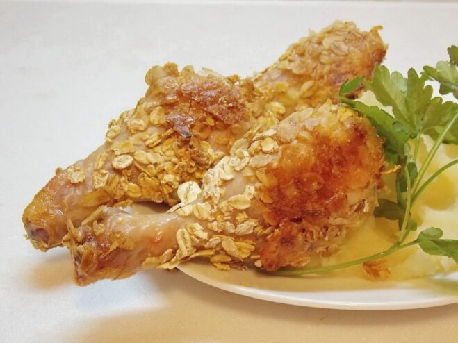 A plate of golden-brown, crispy cereal-crusted chicken drumsticks, ready to be served.