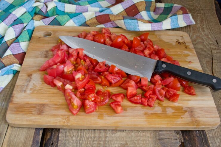 Preparing the tomato base for Lecho A pile of freshly chopped red tomatoes on a cutting board.