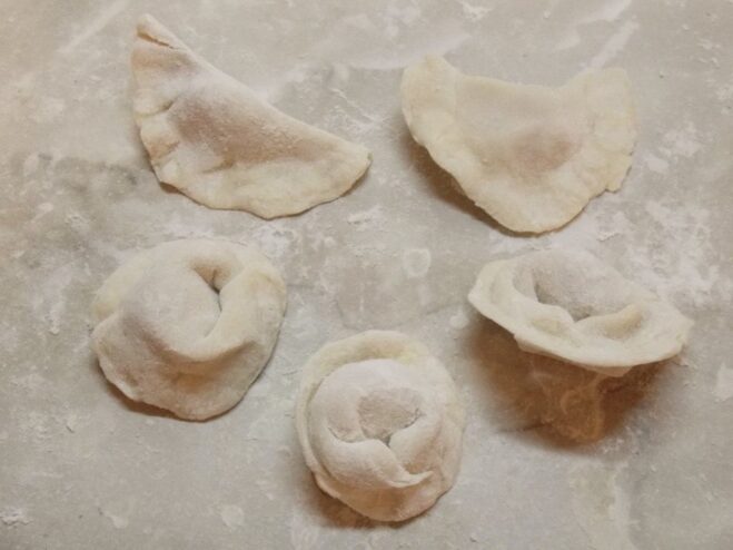 The Classic Pelmeni Shape: Sealing the Dumpling Hands folding a pelmeni dumpling by first sealing it into a half-moon and then joining the corners.