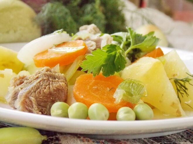 A white bowl filled with freshly made summer vegetable stew, garnished with fresh herbs.