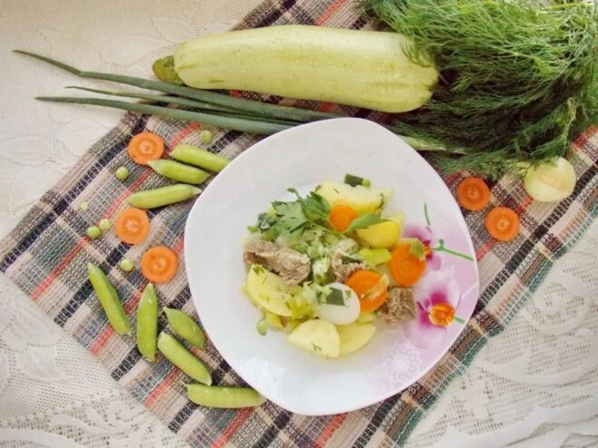 The finished summer vegetable stew, ready to be served. A pot of freshly cooked, vibrant summer stew with young vegetables, ready to eat.