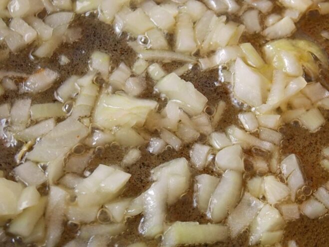 Sautéing Onions for a Flavorful Base Chopped onions being sautéed in a pan until translucent.