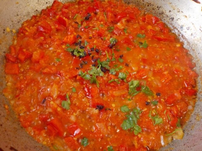 Simmering the Tomato Sauce for Ratatouille Grated tomato pulp being added to the pan with sautéed onions and peppers to create the sauce.