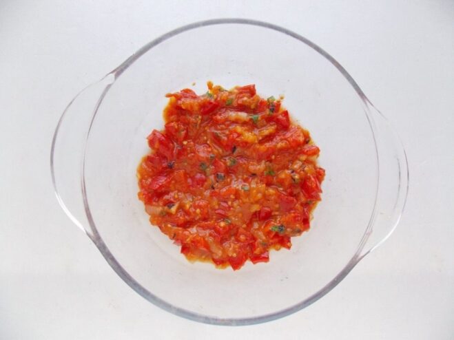 Layering the Sauce in the Baking Dish A layer of rich tomato sauce spread evenly on the bottom of a white baking dish.