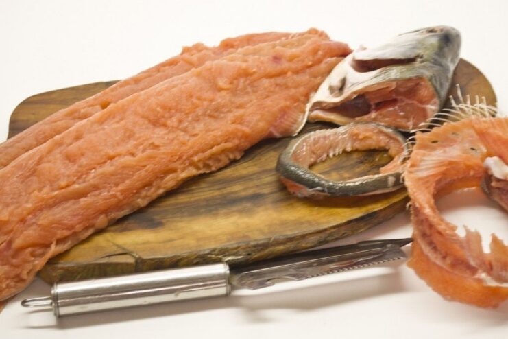 Two fresh pink salmon fillets being prepared on a cutting board.