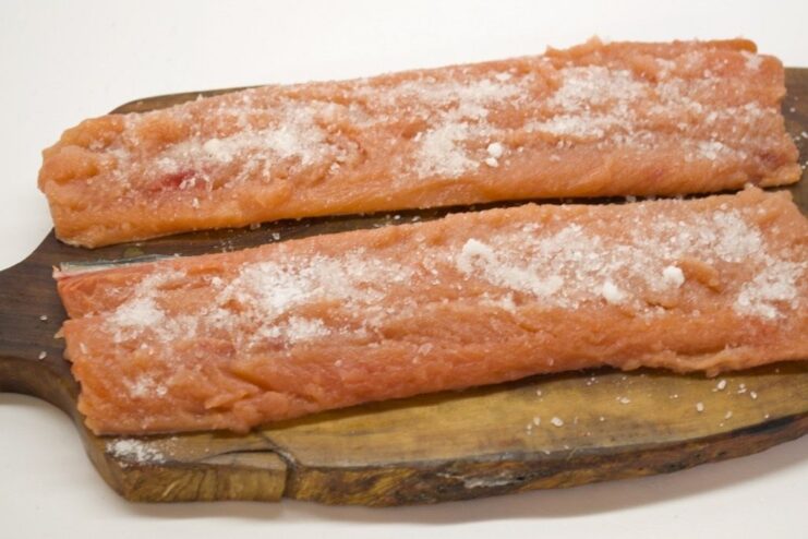 Pink salmon fillets seasoned with salt and sugar, ready to be refrigerated for curing.