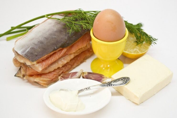 Ingredients for red fish rolls: cured salmon, processed cheese, egg, dill, and garlic laid out on a table.