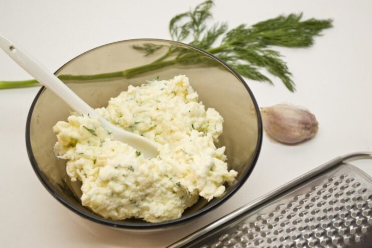 A bowl with the mixed filling for the fish rolls, containing cheese, egg, and dill.