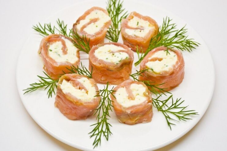 The finished and chilled red fish roll being sliced into individual portions on a cutting board.