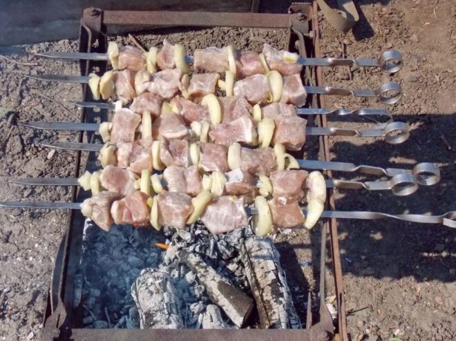 Grilling Shashlik to Perfection on the Mangal Several skewers of shashlik arranged over hot coals on a rectangular mangal grill.