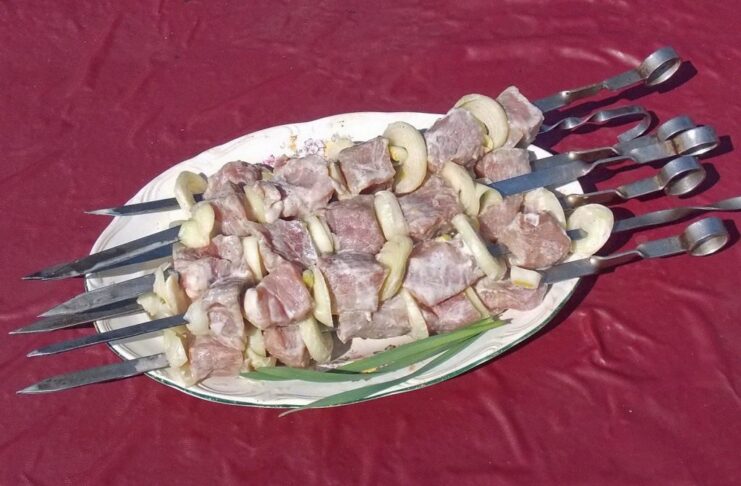 How to Properly Skewer Meat for Evenly Cooked Shashlik Threading marinated meat cubes and onion rings onto a long metal skewer.