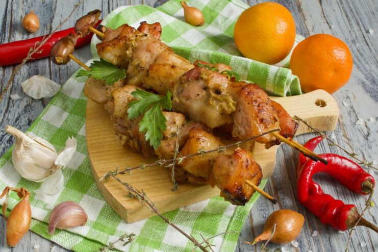 A plate with ready-to-eat pork shashlik on skewers.