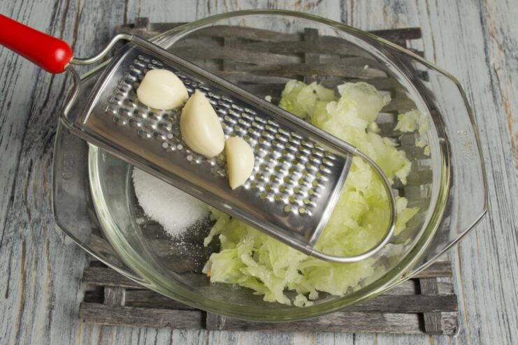 Adding freshly grated garlic to the onion marinade base. Grated garlic is being added to the onion mixture in a bowl.